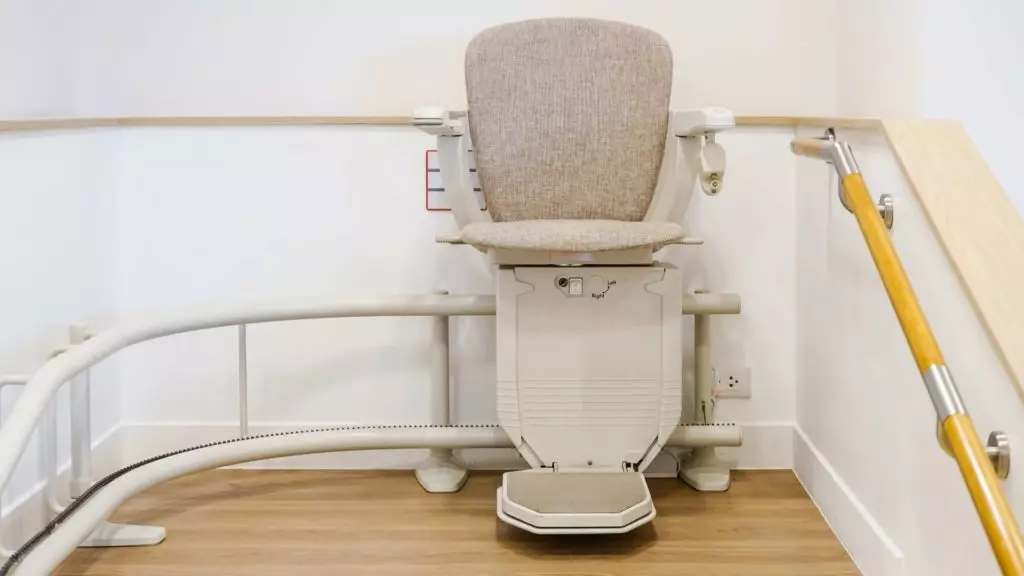Kurven-Treppenlift mit gepolstertem Sitz am Treppenpodest – ein Umbau, für den die Pflegekasse bis zu 4.180 € zuschießt