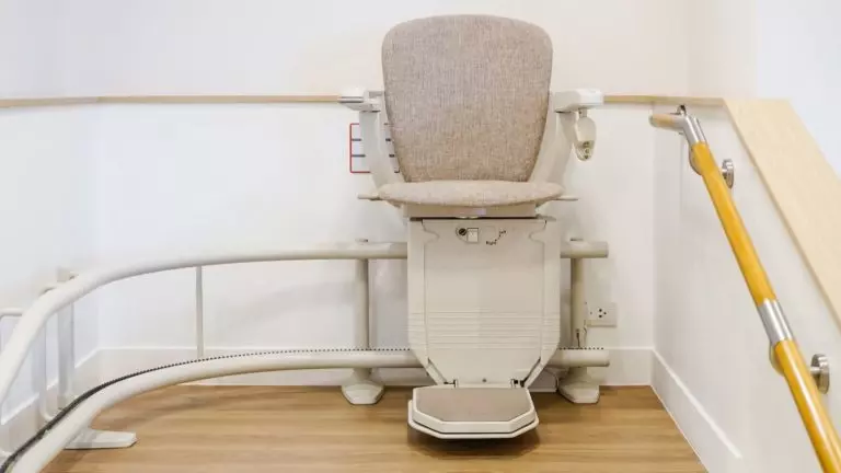 Sitzlift mit gebogener Fahrschiene, geparkt am oberen Ende einer Treppe
