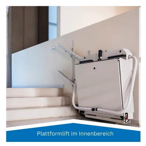 Zusammengeklappter Plattformlift an der Wand am Fuß einer hellen Innentreppe, darunter die Beschriftung Plattformlift im Innenbereich